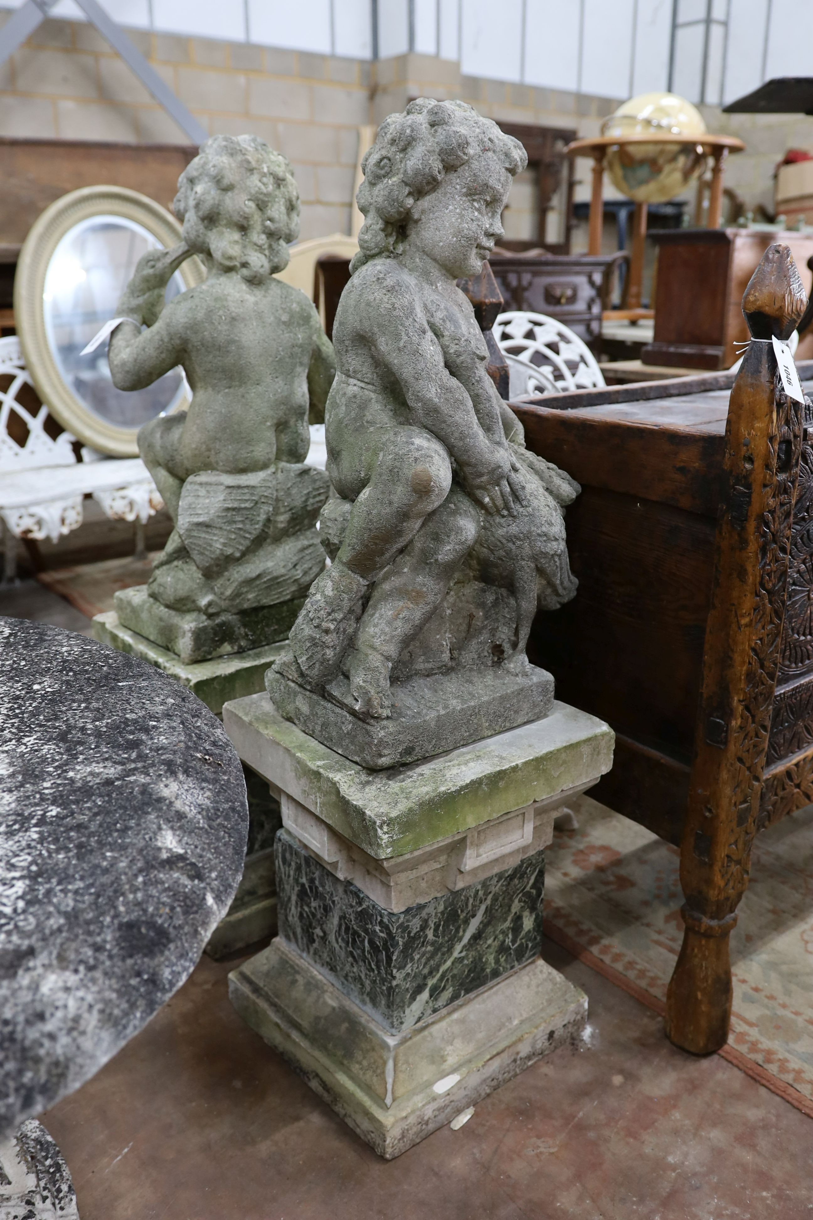 A pair of reconstituted stone cherub and dove garden ornaments on faux marble plinths, height 116cm